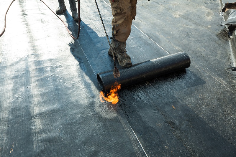 Installation of roll roofing waterproofing propane blowtorch during construction